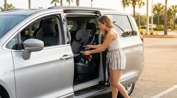 Parent checking the safety harness of a child seat in the backseat of an Orlando car rental
