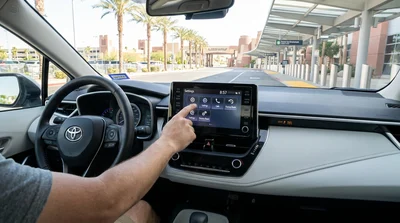 Driver touching the infotainment screen of a Las Vegas car rental with the city skyline visible through the windshield