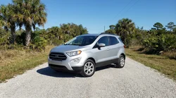 White car rental driving down an unpaved gravel road surrounded by trees in Florida