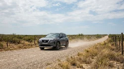 A white car rental driving along a dusty unpaved gravel road in Texas