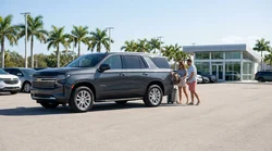 White SUV car rental driving along a sunny coastal highway lined with palm trees in Florida