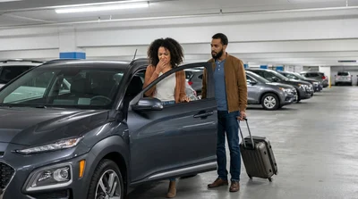 A person inspecting the interior of a vehicle at a car rental lot in New York with tall skyscrapers behind it
