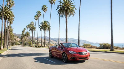 A person driving a white car rental on a sunny highway toward the Los Angeles skyline
