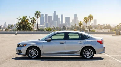 Modern white vehicle leaving a car rental lot with the Los Angeles skyline in the background