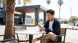 Electric car rental plugged into a public charging station on a sunny palm-lined street in California