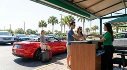 Close-up of a customer handing a credit card to an agent at a car hire desk in Florida