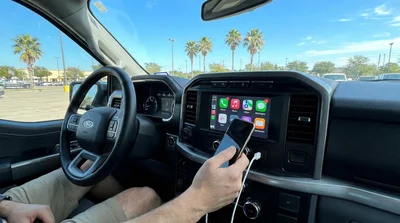Smartphone connected to a dashboard screen via USB cable inside a Texas car rental