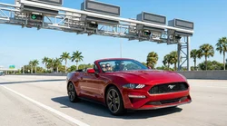 White car rental approaching an electronic toll plaza on a sunny Florida highway