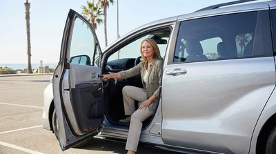 Driver gripping a steering wheel spinner knob during a car rental road trip on a sunny California highway