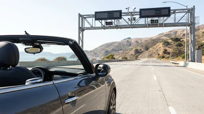 Silver car rental driving across the Golden Gate Bridge in San Francisco on a sunny day