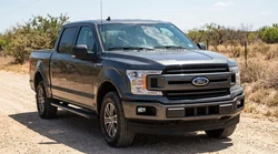 A white car rental driving on a sunny Texas highway with a clear view of the windscreen and tyres