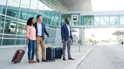 Travelers with luggage waiting for a car hire shuttle outside Newark Terminal C in New York