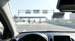 Silver car rental driving through an electronic toll plaza on a New York highway