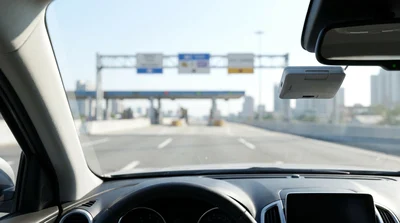 Silver car rental driving through an electronic toll plaza on a New York highway