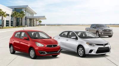White economy and silver compact cars parked side by side at a sunny car rental lot in Texas