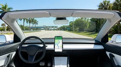 Smartphone displaying a navigation map on the dashboard of a car rental parked on a sunny Florida street