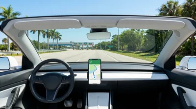 Smartphone displaying a navigation map on the dashboard of a car rental parked on a sunny Florida street