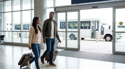 Travelers with luggage walking past signs for the car rental center at Philadelphia Airport in Pennsylvania
