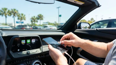 Person plugging a phone into a dashboard screen with a USB cable inside a car rental in Orlando