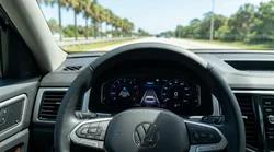 Steering wheel with cruise control buttons inside a modern car hire driving on a sunny Florida highway