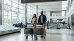 Traveler pulling luggage past a baggage claim carousel towards the car rental center in Miami