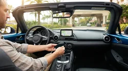 Person touching a car dashboard screen showing mobile navigation in an Orlando car rental