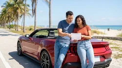 Person driving a car rental along a sunny coastal highway lined with palm trees in Florida