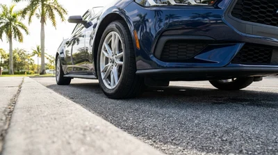 Front wheel and underbody of a modern car rental parked next to a concrete street curb in Florida