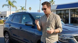 A driver receiving keys to a white SUV at an outdoor California car rental lot