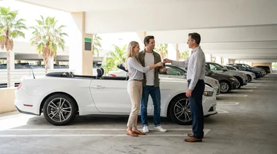 Traveler loading luggage into a parked vehicle at a sunny car rental lot in Miami
