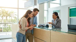 Person holding a credit card over a payment terminal at a car hire desk in Florida