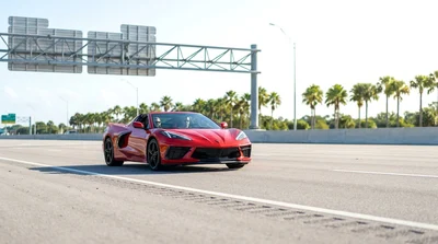 White car rental driving under a highway toll gantry in sunny Florida