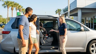 A parent fitting a child safety seat into the back of an Orlando car rental vehicle