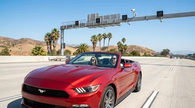 White car rental driving under an electronic highway toll booth in California