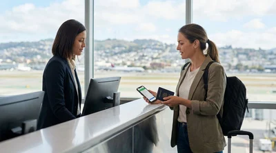 Passenger with luggage receiving keys at a San Francisco airport car rental counter