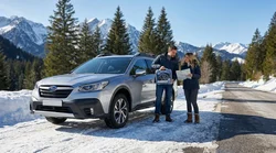 White SUV car rental equipped with snow chains driving on a snowy mountain road in California