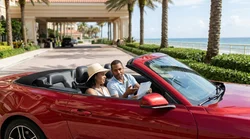 A white car hire driving on a sunny highway lined with palm trees in Florida