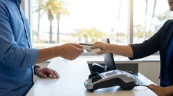 Close up of a person handing a credit card to an agent at a car hire desk in California