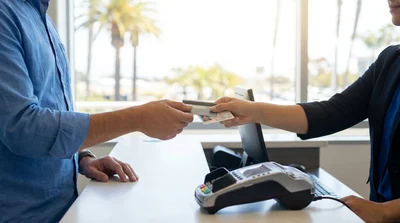 Close up of a person handing a credit card to an agent at a car hire desk in California