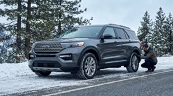 White SUV car rental equipped with snow chains parked on a snowy mountain road in California