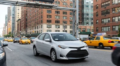 A modern car rental navigating heavy traffic on a busy street in New York
