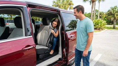 Close-up of a child safety seat secured by a top tether anchor in the backseat of a car rental in Florida