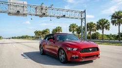 Person driving a car rental through a sunny Florida highway toll plaza