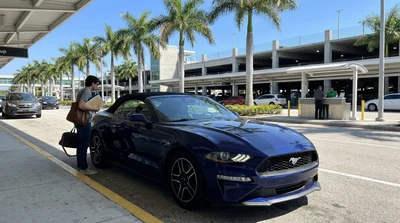 Driver holding the steering wheel of a car rental on a sunny coastal road in Florida
