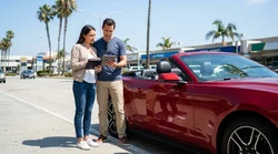 Close-up of a customer signing car rental paperwork at a desk in California