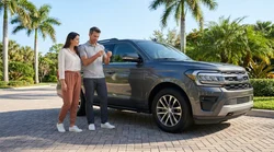 Silver SUV car rental driving along a sunny coastal road lined with palm trees in Florida