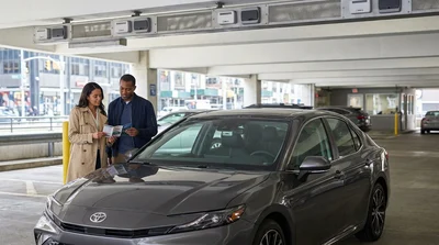 Driver in a car rental approaching an overhead toll sign on a New York bridge