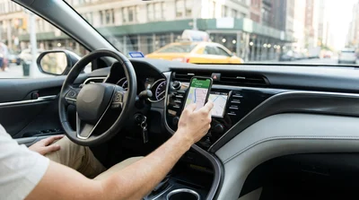 Smartphone secured to a dashboard mount inside a car rental with New York traffic visible through the windshield
