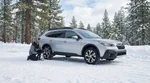 Silver car rental with snow chains on its tires driving along a snowy mountain highway in California