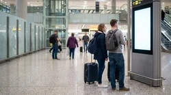 Travelers with luggage walking through Philadelphia Airport in Pennsylvania toward the car rental desks